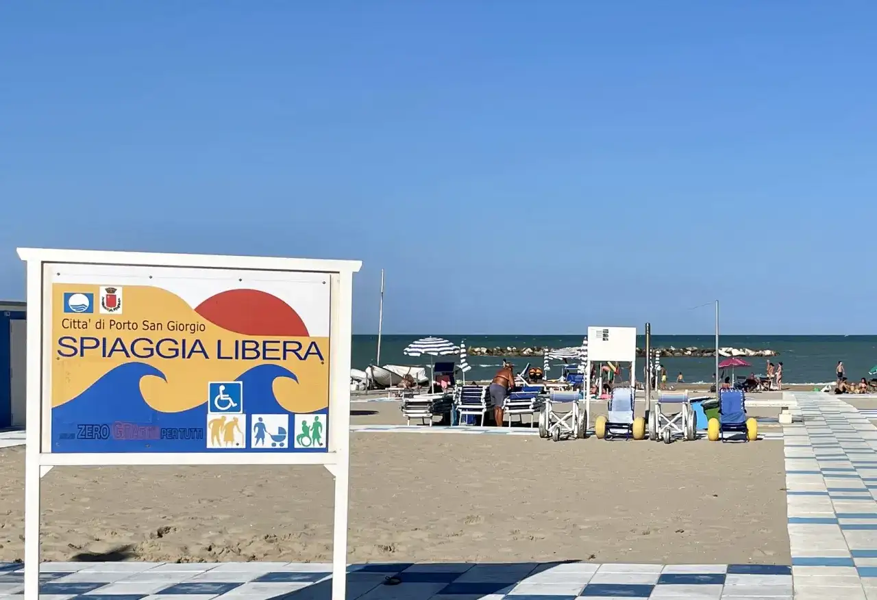 Cartello "Spiaggia Libera" a Porto San Giorgio, con simboli per accessibilità e famiglie.