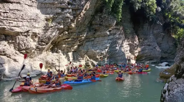 Gruppo in canoa esplora un canyon con pareti rocciose imponenti, navigando tra le marmitte dei giganti scavate dall'acqua.